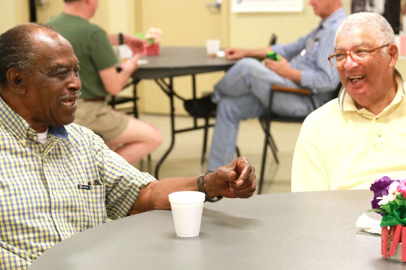 two men at a table talking and laughing