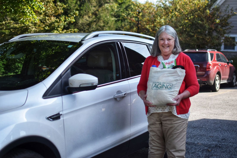 woman holding a bag in front of a car